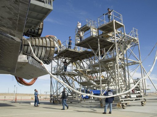 echnicians monitor the positioning of a workstand as it is moved into place around the main engines of the shuttle Endeavour during deservicing at NASA DFRC