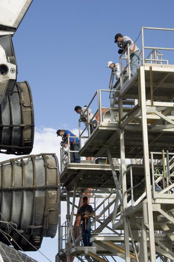 Technicians monitor the positioning of a workstand as it is moved into place around the main engines of the shuttle Endeavour during deservicing at NASA DFRC
