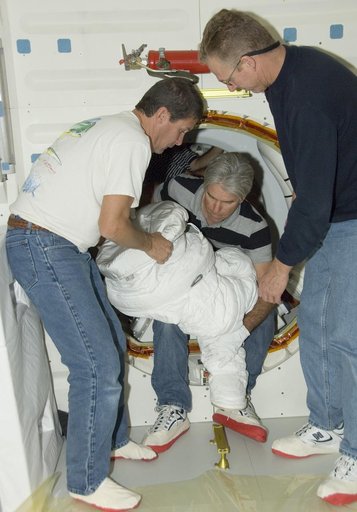 Technicians Troy Mann, Mark Shimei and Jim Smodell remove the lower portion of an Extravehicular Mobility Unit (EMU) suit from Endeavour's airlock