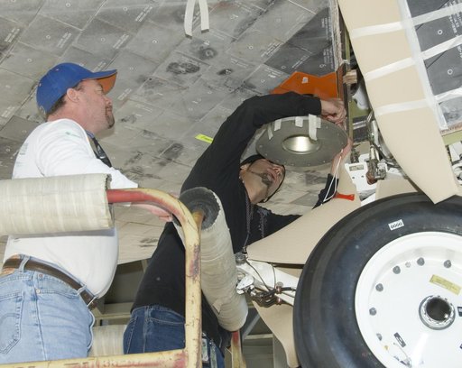 Mark Burton and Russell Wazniak attach the forward mount fixture to Shuttle Endeavour for mounting the orbiter to the 747 Shuttle Carrier Aircraft