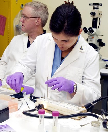 KENNEDY SPACE CENTER, FLA. -  Valerie Cassanto (foreground), Instrumentation Technology Associates, Inc., examines one of the experiments carried on mission STS-107. Several experiments were found during the search for Columbia debris. Included in the Commercial ITA Biomedical Experiments payload on