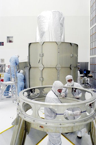 KENNEDY SPACE CENTER, FLA. -  Workers in NASA Spacecraft Hangar AE (background) remove sections of the transportation canister from around the Space Infrared Telescope Facility (SIRTF), which has been returned to the hangar from the launch pad.   Additional workers (foreground) prepare the Delta pay