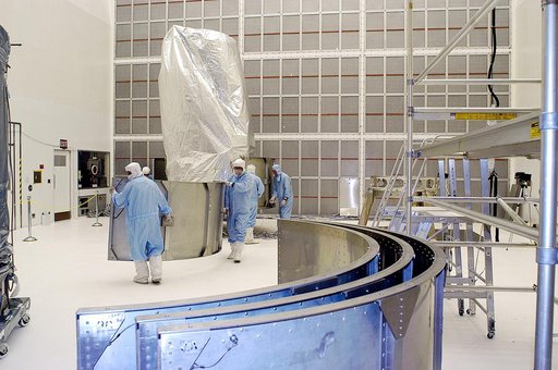 KENNEDY SPACE CENTER, FLA. -  Workers in NASA Spacecraft Hangar AE remove sections of the transportation canister from around the Space Infrared Telescope Facility (SIRTF), which has been returned to the hangar from the launch pad.   SIRTF will remain in the clean room until it returns to the pad in