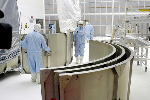 KENNEDY SPACE CENTER, FLA. -  Workers in NASA Spacecraft Hangar AE remove sections of the transportation canister from around the Space Infrared Telescope Facility (SIRTF), which has been returned to the hangar from the launch pad.   SIRTF will remain in the clean room until it returns to the pad in