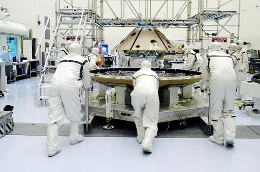 KENNEDY SPACE CENTER, FLA. - In the Payload Hazardous Servicing Facility, workers move the heat shield (foreground) toward the upper backshell/ Mars Exploration Rover 1 (MER-1), in the background.  The backshell and heat shield will be mated.  NASA's twin Mars Exploration Rovers are designed to stud