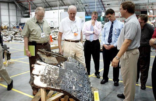 KENNEDY SPACE CENTER, FLA. - Adm. Harold Gehman, center, chairman of the Columbia Investigation Accident Board,  looks at a large piece of Columbia debris in the RLV Hangar.  He and other board members are visiting the Hangar as part of the ongoing investigation.  To the right of Gehman are U.S. Rep