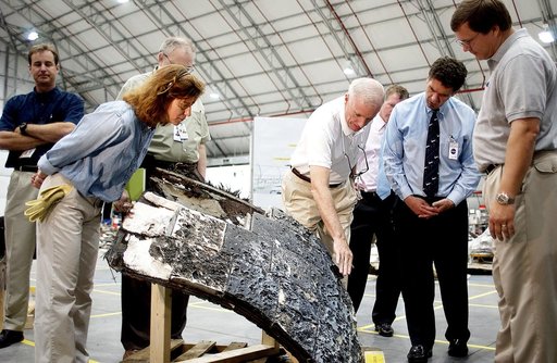 KENNEDY SPACE CENTER, FLA. - In the RLV Hangar, Adm. Harold Gehman, center, chairman of the Columbia Investigation Accident Board, gestures toward a large piece of Columbia debris.  He and other board members are visiting the Hangar as part of the ongoing investigation.  At right is U.S. Representat