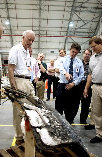 KENNEDY SPACE CENTER, FLA. - In the RLV Hangar, Adm. Harold Gehman, center, chairman of the Columbia Investigation Accident Board, looks on while U.S. Representative Dave Weldon (second from right) points at a piece of Columbia debris.  Behind Gehman is U.S. Representative Tom Feeney.  Gehman and ot