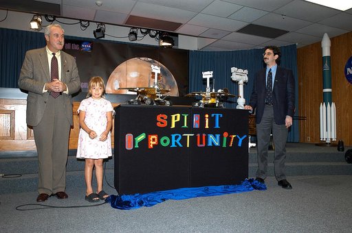 KENNEDY SPACE CENTER, FLA. -  Nine-year-old Sofi Collis proudly presents the names she selected for the Mars Exploration Rovers  -- "Spirit" and "Opportunity" --  during a press conference.  Also participating in the press conference are NASA Administrator Sean O'Keefe (left) and Brad Justus, LEGO C