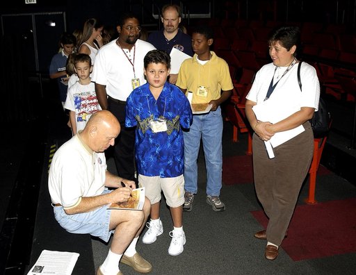 KENNEDY SPACE CENTER, FLA.  -   Former astronaut Story Musgrave signs autographs for employees’ children after his presentation during a welcome ceremony in the IMAX Theatre, KSC Visitor Complex.  Employees were invited to share their work experience with their children for Take Our Children to Work