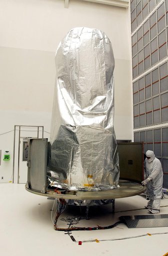 KENNEDY SPACE CENTER, FLA.  -  A worker at Hangar A&E, Cape Canaveral Air Force Station, place the lower panels of the canister around the Space Infrared Telescope Facility (SIRTF).  The spacecraft will be transported to Launch Complex 17-B for mating with its launch vehicle, the Delta II rocket.   