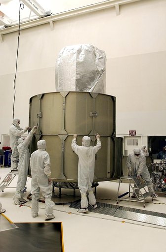 KENNEDY SPACE CENTER, FLA.  - Workers at Hangar A&E, Cape Canaveral Air Force Station, place the middle row of panels to encapsulate the Space Infrared Telescope Facility (SIRTF).  The spacecraft will be transported to Launch Complex 17-B for mating with its launch vehicle, the Delta II rocket.   SI