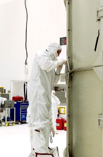 KENNEDY SPACE CENTER, FLA.  - A worker at Hangar A&E, Cape Canaveral Air Force Station, tightens the canister around the Space Infrared Telescope Facility (SIRTF).  The spacecraft will be transported to Launch Complex 17-B for mating with its launch vehicle, the Delta II rocket.   SIRTF consists of 