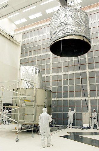 KENNEDY SPACE CENTER, FLA.  - Workers at Hangar A&E, Cape Canaveral Air Force Station, help guide the upper canister toward the Space Infrared Telescope Facility (SIRTF) at left.  After encapsulation is complete, the spacecraft will be transported to Launch Complex 17-B for mating with its launch ve