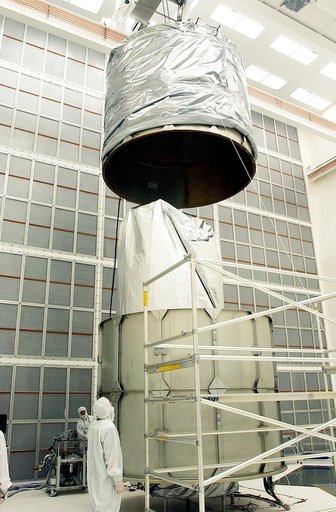KENNEDY SPACE CENTER, FLA.  - Workers at Hangar A&E, Cape Canaveral Air Force Station, lower the upper canister toward the Space Infrared Telescope Facility (SIRTF) below.  After encapsulation is complete, the spacecraft will be transported to Launch Complex 17-B for mating with its launch vehicle, 