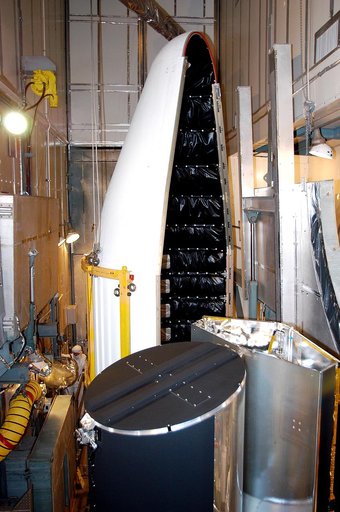 KENNEDY SPACE CENTER, FLA.  - In the mobile service tower on Launch Pad 17-B, Cape Canaveral Air Force Station, the first half of the fairing (background) moves toward the Space Infrared Telescope Facility (foreground) for encapsulation. SIRTF will obtain images and spectra by detecting the infrared