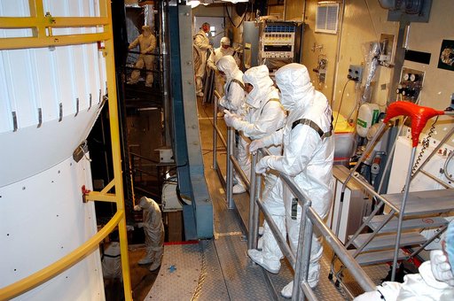 KENNEDY SPACE CENTER, FLA.  - In the mobile service tower on Launch Pad 17-B, Cape Canaveral Air Force Station, workers watch as the first half of the fairing moves closer around the Space Infrared Telescope Facility (SIRTF). SIRTF will obtain images and spectra by detecting the infrared energy, or 