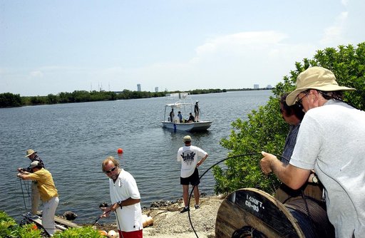 KENNEDY SPACE CENTER, FLA.  -  Research team members roll out acoustic cable to the water's edge as others stand by in a watercraft during underwater acoustic research being conducted in the Launch Complex 39 turn basin.  Several government agencies, including NASA, NOAA, the Navy, the Coast Guard, 