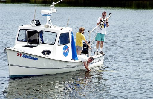 KENNEDY SPACE CENTER, FLA.  -  A research team member aboard one of the watercraft being utilized to conduct underwater acoustic research in the Launch Complex 39 turn basin releases some of the project's equipment into the water.  Several government agencies, including NASA, NOAA, the Navy, the Coa