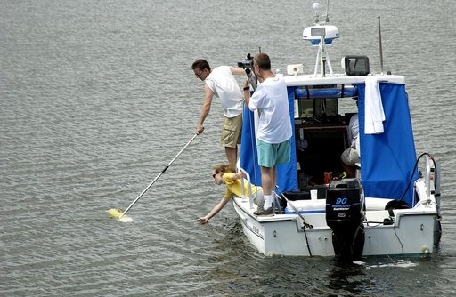 KENNEDY SPACE CENTER, FLA.  -  Research team members aboard one of the watercraft being utilized to conduct underwater acoustic research in the Launch Complex 39 turn basin retrieve some of the project's equipment from the water.  Several government agencies, including NASA, NOAA, the Navy, the Coas