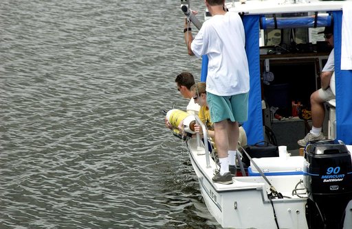 KENNEDY SPACE CENTER, FLA.  -  A research team member aboard one of the watercraft being utilized to conduct underwater acoustic research in the Launch Complex 39 turn basin lifts some of the project's equipment from the water.  Several government agencies, including NASA, NOAA, the Navy, the Coast 