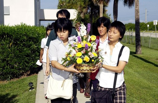 KENNEDY SPACE CENTER, FLA.  -    Japanese girls from Urawa Daiichi Girls High School, Urawa, Japan, carry a floral tribute to the crew of Columbia to place at the STS-107 memorial stone at the Spacehab facility, Cape Canaveral, Fla.   The group was  awarded the trip to Florida when their experiments