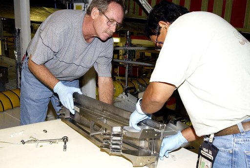 KENNEDY SPACE CENTER, FLA. - Technician Saul Ngy, with United Space Alliance, prepares to install a spar on the wing of the orbiter Atlantis.  The Reinforced Carbon Carbon (RCC) panels are mechanically attached to the wing with a series of floating joints - spars - to reduce loading on the panels ca