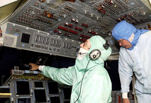 KENNEDY SPACE CENTER, FLA.  -  During power-up of the orbiter Discovery in the Orbiter Processing Facility, a technician (left) looks at the circuit breaker lights in the cabin.  Discovery has been undergoing Orbiter Major Modifications in the past year, ranging from wiring, control panels and black