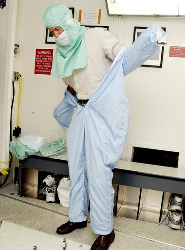 KENNEDY SPACE CENTER, FLA. -  A KSC employee dons the coverall of a "bunny suit," part of standard clean room apparel, before entering a clean room. The apparel is designed to cover the hair, clothing and shoes of employees to prevent particulate matter from contaminating the space flight hardware b