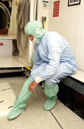 KENNEDY SPACE CENTER, FLA. -  A KSC employee secures a foot and leg cover of his "bunny suit," part of standard clean room apparel, before entering a clean room. The apparel is designed to cover the hair, clothing and shoes of employees to prevent particulate matter from contaminating the space flig