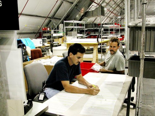 KENNEDY SPACE CENTER, FLA.  -  Workers in the Columbia Debris Hangar record the first items of the STS-107 debris to be transferred to storage in the Vehicle Assembly Building.   About 83,000 pieces were shipped to KSC during search and recovery efforts in East Texas.