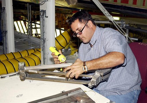 KENNEDY SPACE CENTER, FLA. - In the Orbiter Processing Facility, John Newport, with United Space Alliance, inspects a spar to be installed on the wing of the orbiter Atlantis.  Reinforced Carbon Carbon (RCC) panels are mechanically attached to the wing with a series of floating joints - spars - to r