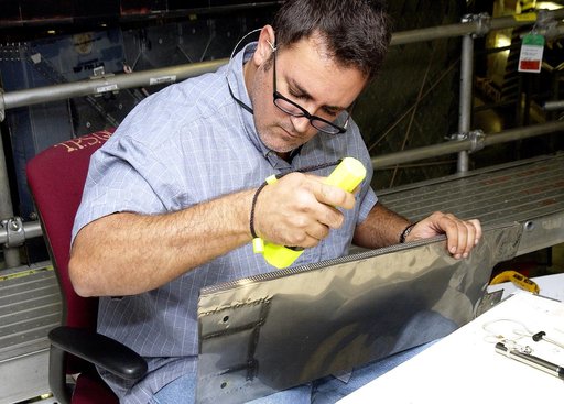 KENNEDY SPACE CENTER, FLA. - In the Orbiter Processing Facility, John Newport, with United Space Alliance, inspects a piece of equipment for spar installation on the wing of the orbiter Atlantis.  Reinforced Carbon Carbon (RCC) panels are mechanically attached to the wing with a series of floating j