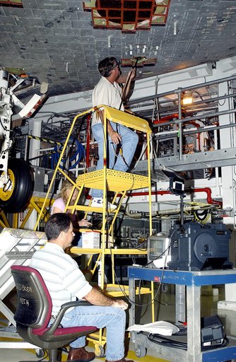 KENNEDY SPACE CENTER, FLA. -   In the Orbiter Processing Facility, while Greg Harlow, with United Space Alliance (USA) (above) threads a camera under the tiles of the orbiter Endeavour, Peggy Ritchie, USA, (behind the stand) and NASA’s Richard Parker (seated) watch the images on a monitor to inspect