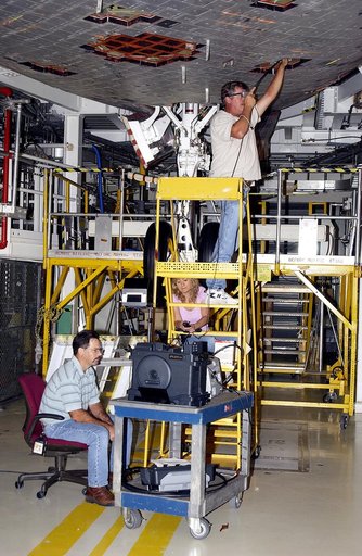 KENNEDY SPACE CENTER, FLA. -  In the Orbiter Processing Facility, while Greg Harlow, with United Space Alliance (USA), (above) threads a camera under the tiles of the orbiter Endeavour, Peggy Ritchie, with USA, (behind the stand) and NASA’s Richard Parker watch the images on a monitor to inspect for