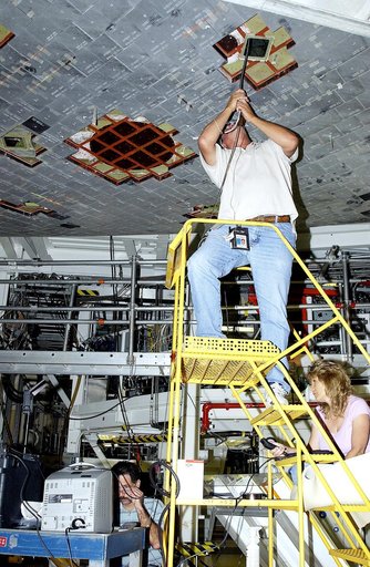 KENNEDY SPACE CENTER, FLA. - In the Orbiter Processing Facility, while Greg Harlow, with United Space Alliance (USA), (above) threads a camera under the tiles of the orbiter Endeavour, NASA’s Richard Parker (below left) and Peggy Ritchie, with USA, (at right) watch the images on a monitor to inspect