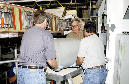 KENNEDY SPACE CENTER, FLA. - In the Orbiter Processing Facility, United Space Alliance workers Mike Hyatt (left) Jerry Belt (center), and Saul Ngy (right), lift a Reinforced Carbon Carbon (RCC) panel they will attach to the leading edge of the wing of the orbiter Atlantis.  The gray carbon composite