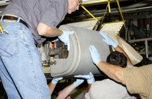 KENNEDY SPACE CENTER, FLA. - In the Orbiter Processing Facility, United Space Alliance workers Mike Hyatt (left) Saul Ngy (center) and Jerry Belt (right) lift a Reinforced Carbon Carbon (RCC) panel to attach onto the leading edge of the wing of the orbiter Atlantis.  The gray carbon composite RCC pa