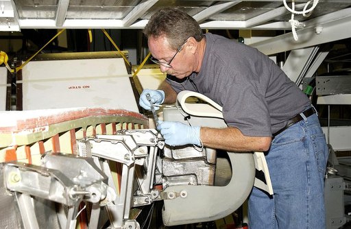 KENNEDY SPACE CENTER, FLA. -  In the Orbiter Processing Facility, United Space Alliance worker Mike Hyatt attaches a Reinforced Carbon Carbon (RCC) panel onto the leading edge of the wing of the orbiter Atlantis.  The gray carbon composite RCC panels have sufficient strength to withstand the aerodyn
