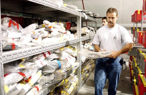 KENNEDY SPACE CENTER, FLA. -  In the Columbia Debris Hangar,  Don Eitel (in front) and Jim Delie carry pieces of debris to be packed into storage boxes.  About 83,000 pieces of debris were shipped to KSC during search and recovery efforts in East Texas. That represents about 38 percent of the dry we