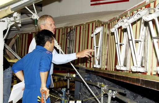 KENNEDY SPACE CENTER, FLA. -  William Gaetjens (background), with the Vehicle Integration Test Team (VITT) directs Japanese astronaut Koichi Wakata’s attention to the spars installed on the wing of the orbiter Atlantis.  Reinforced Carbon Carbon (RCC) panels are mechanically attached to the wing via