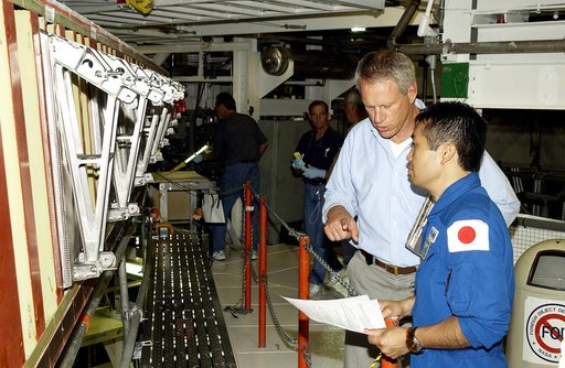 KENNEDY SPACE CENTER, FLA. - Japanese astronaut Koichi Wakata (right) listens to William Gaetjens, with the Vehicle Integration Test Team (VITT), who is providing details about the spar installation (left) on the wing of the orbiter Atlantis.  Reinforced Carbon Carbon (RCC) panels are mechanically a