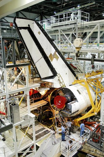 KENNEDY SPACE CENTER, FLA. -  Workers in the Orbiter Processing Facility prepare to remove one of two orbital maneuvering system (OMS) pods from Endeavour.  The OMS pods are attached to the upper aft fuselage left and right sides.  Fabricated primarily of graphite epoxy composite and aluminum, each 