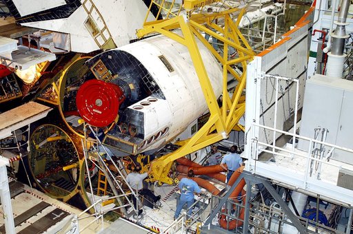 KENNEDY SPACE CENTER, FLA. -  Workers in the Orbiter Processing Facility prepare to remove one of two orbital maneuvering system (OMS) pods from Endeavour.  The OMS pods are attached to the upper aft fuselage left and right sides.  Fabricated primarily of graphite epoxy composite and aluminum, each 