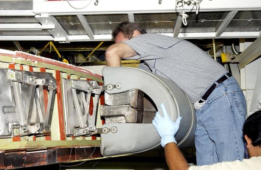 KENNEDY SPACE CENTER, FLA. - In the Orbiter Processing Facility, United Space Alliance workers Mike Hyatt (above) and Saul Ngy (below right) finish installing a Reinforced Carbon Carbon (RCC) panel to the leading edge of the wing of the orbiter Atlantis.  The gray carbon composite RCC panels have su