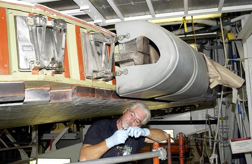 KENNEDY SPACE CENTER, FLA. -   Billy Witt, a midbody shop mechanic with United Space Alliance, checks a part used for installation of a Reinforced Carbon Carbon (RCC) panel to the leading edge of the wing of an orbiter.  Above him is an RCC panel just installed on Atlantis.  The gray carbon composit