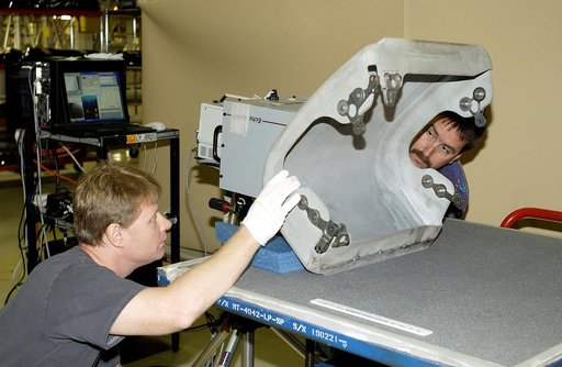 KENNEDY SPACE CENTER, FLA. -  In the Orbiter Processing Facility,  Jim Landy (left), NDE specialist with United Space Alliance (USA), prepares to examine a Reinforced Carbon Carbon panel using flash thermography.  Helping out, at right, is Dan Phillips, also with USA.  Attached to the leading edge o