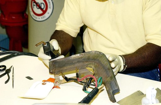 KENNEDY SPACE CENTER, FLA. - United Space Alliance employee Anthony Simmons checks the electroweld he performed on an insulator inside a Reinforced Carbon Carbon panel.   The gray carbon composite RCC panels are attached to the leading edge of the wing of the orbiters to withstand the aerodynamic fo