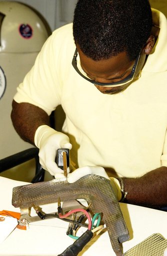 KENNEDY SPACE CENTER, FLA. -   United Space Alliance employee Anthony Simmons continues electrowelding on an insulator inside a Reinforced Carbon Carbon panel.   The gray carbon composite RCC panels are attached to the leading edge of the wing of the orbiters to withstand the aerodynamic forces expe