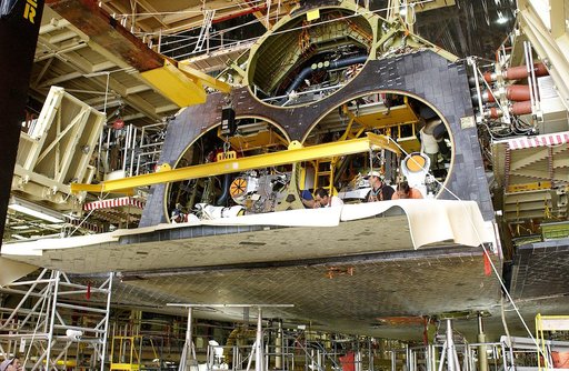 KENNEDY SPACE CENTER, FLA. - In the Orbiter Processing Facility, the rear body flap is lifted into place on the orbiter Discovery.  The body flap, which is temporarily under protective covering,  attaches below the main engines.